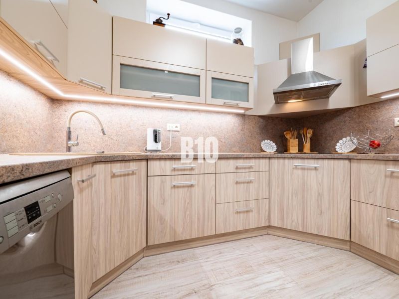 A kitchen in a family house with a wooden decor floor and light furniture.