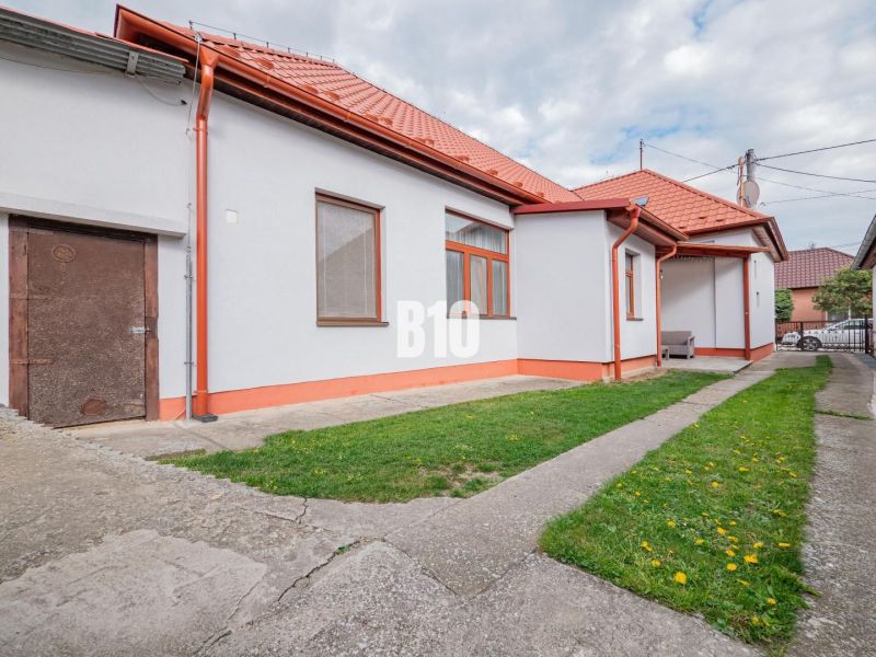 A family house in Nitra with a red roof, a yard, and simple garden landscaping.