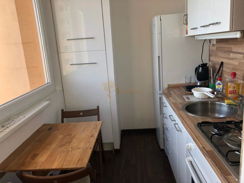 A small kitchen with a wooden table, white cabinets, and a floor with a wooden design.