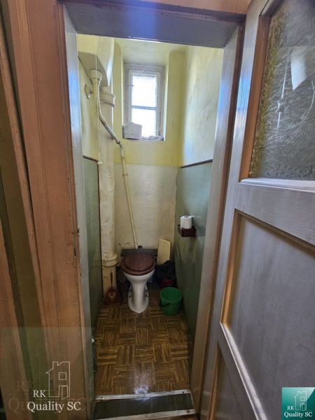 A bathroom in a 2-room apartment with a window and a floor with a wooden decor.