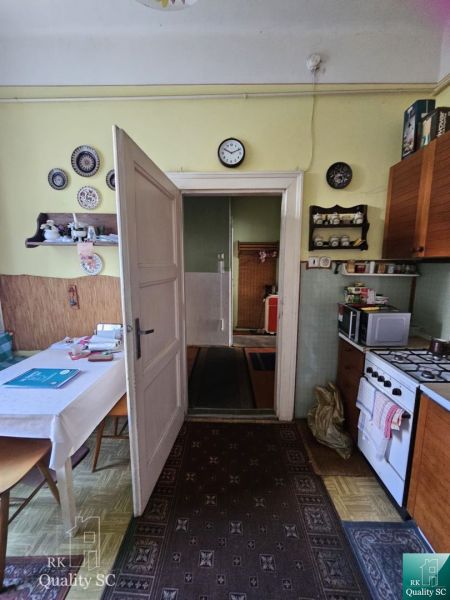 A kitchen in a 2-room apartment with a gas stove, table, carpet, and decorations on the walls.