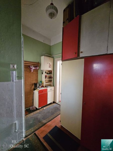 The entrance hallway of a 2-room apartment with green walls and cabinets in red and white colors.