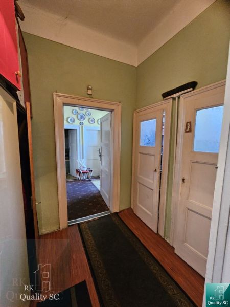 A hallway with an entrance to a room and a floor with a wooden decor in a 2-room apartment.