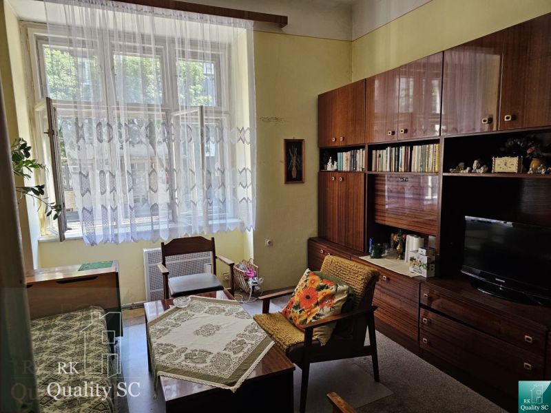 Living room in a two-room apartment with retro furniture and a large window.