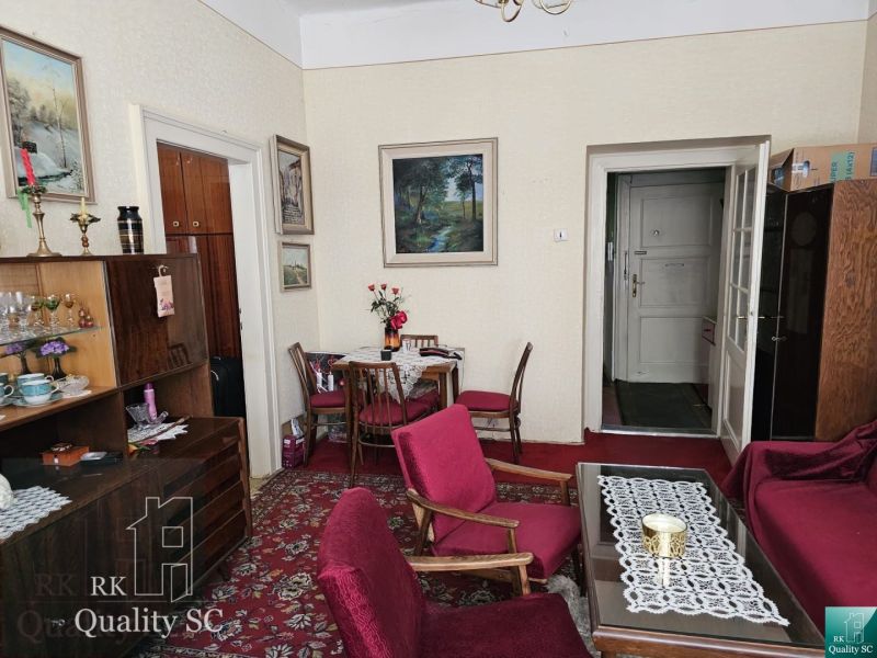 Living room in a two-room apartment with a red carpet and wooden furniture.