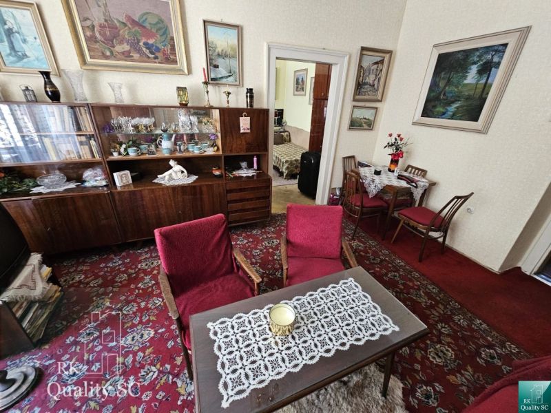 Living room in a two-room apartment with a red carpet and a wooden wall unit.