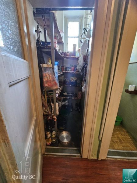 Pantry in a 3-room apartment with shelves and a window, various storage items.