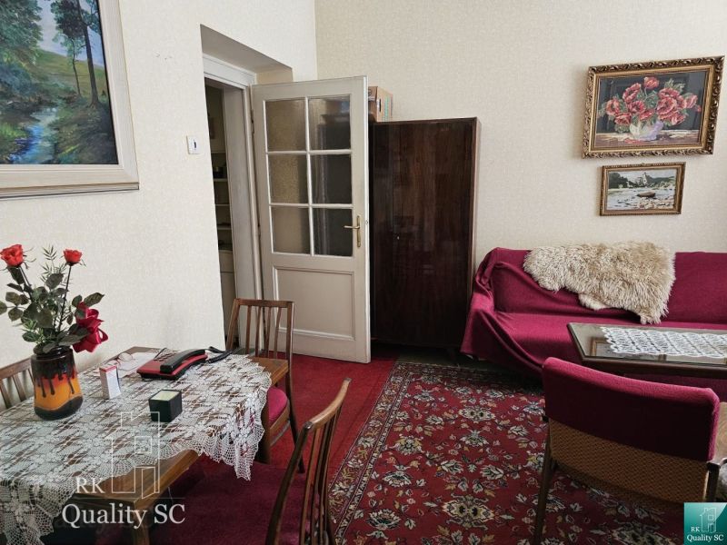 A classic living space in a 2-room apartment with a red carpet and paintings.