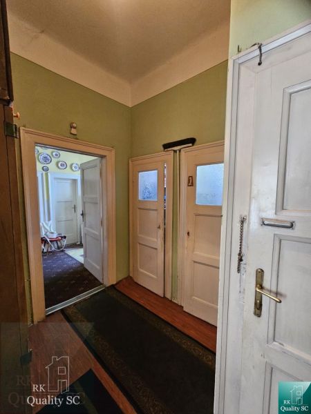 A hallway with pale walls and doors in a 2-room apartment, a floor with a wooden decor.