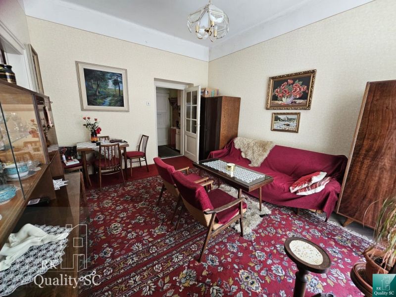 Living room in a 2-room apartment with a carpet and wooden furniture, paintings on the walls.
