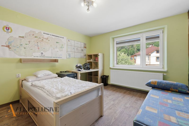A room in a family house with a map on the wall, a bed, and a wooden decor floor.