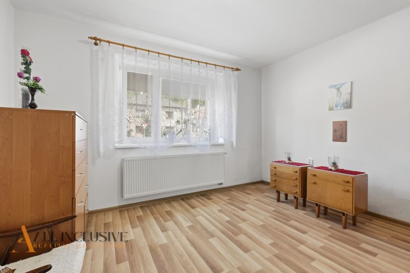 A room in a family house with a wooden decor floor, furniture, and white curtains.