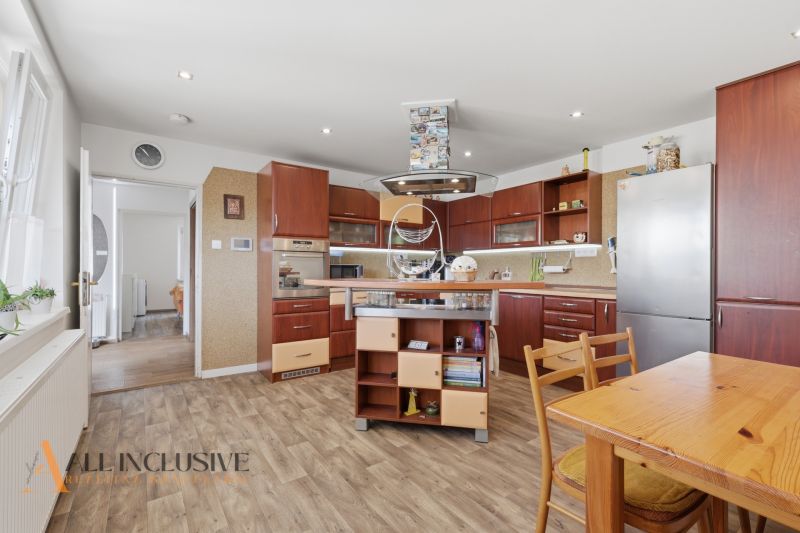 A kitchen with a wooden decor floor, wooden furniture, and appliances in a family house.