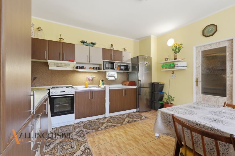 A kitchen in a family house with a wooden decor floor, a dining table, and appliances.