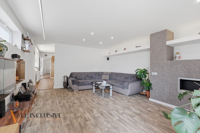 Living room in a family house with a sofa and wood-patterned flooring.