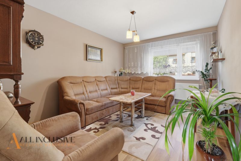 Living room in a family house with a comfortable sofa, carpet, and wooden decor flooring.