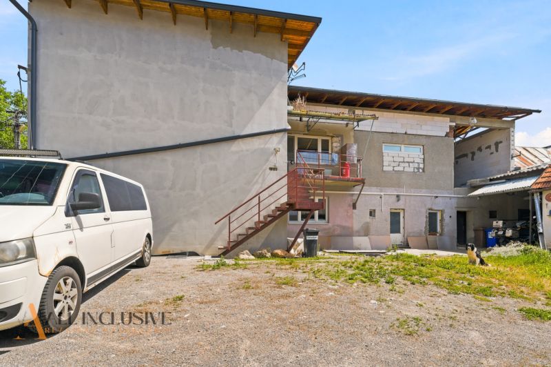 A family house in the village of Dúbravica with a balcony, staircase, and a white van parked next to it.