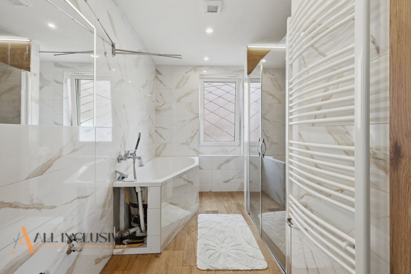 A bathroom with a bathtub and a wooden decor floor in a family house, bright interior.