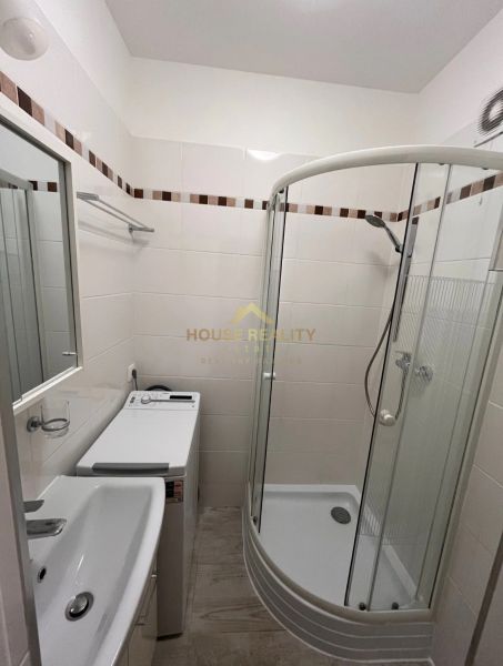 Bathroom with a shower, sink, and washing machine in a studio apartment.