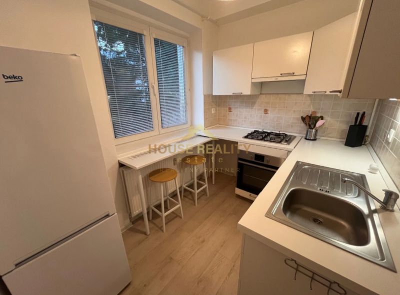 A kitchen in a studio apartment with a breakfast bar and a wooden decor floor.