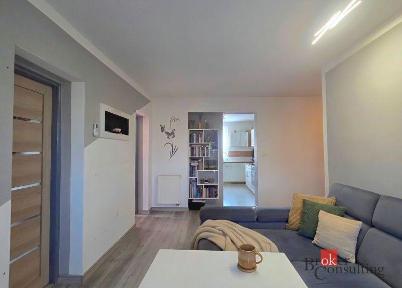 Living room with wooden floor decor and comfortable seating in a 4-room apartment.