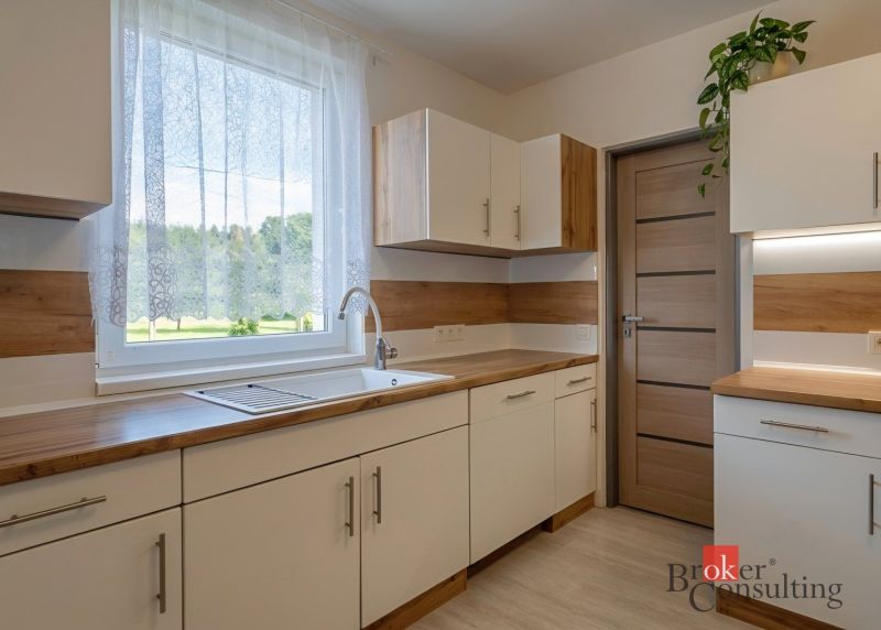 A kitchen in a 4-room apartment with a wooden decor floor and a view of the garden.