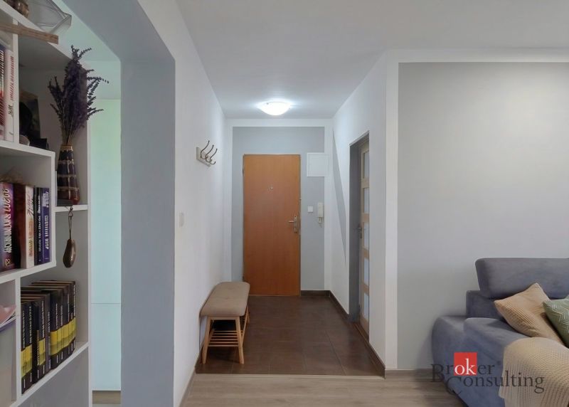 A hallway in a 4-room apartment with a bench and a bookshelf.