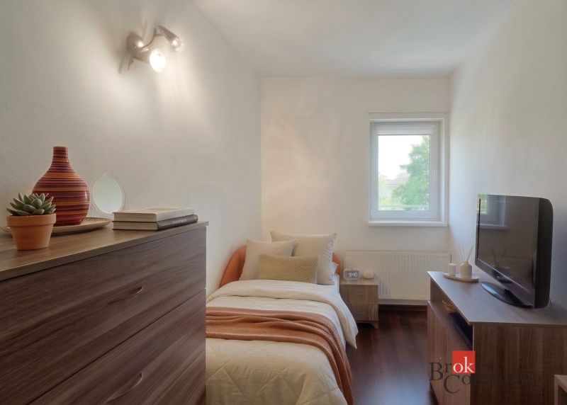 Bedroom in a 4-room apartment with wood-patterned flooring and simple furnishings.