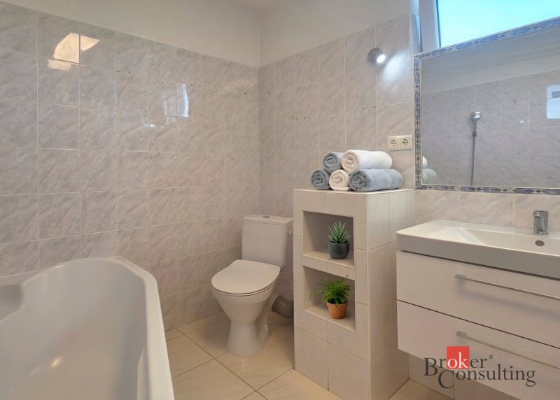 Bathroom in a 4-room apartment with a bathtub, sink, and toilet, light tiles.