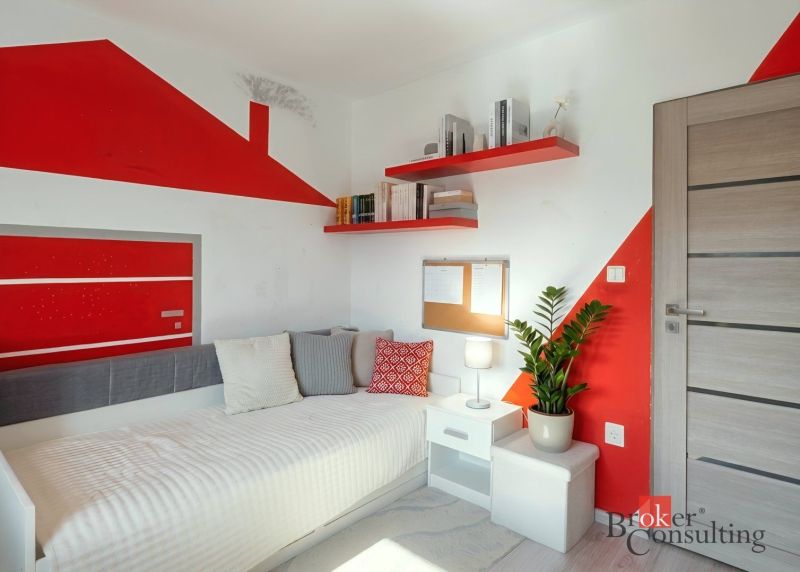 A children's room in a 4-room apartment with red decorations and simple furniture.