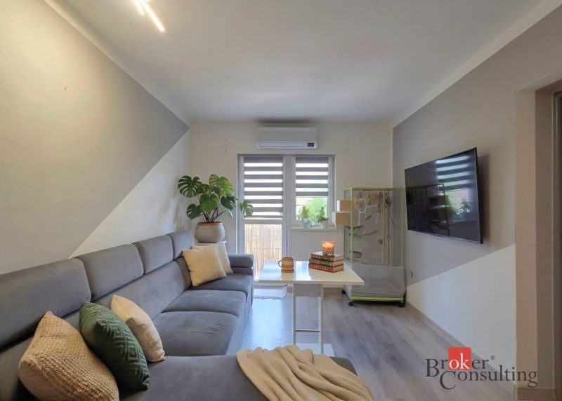 Living room in a 4-room apartment with a comfortable sofa and a TV on the wall.