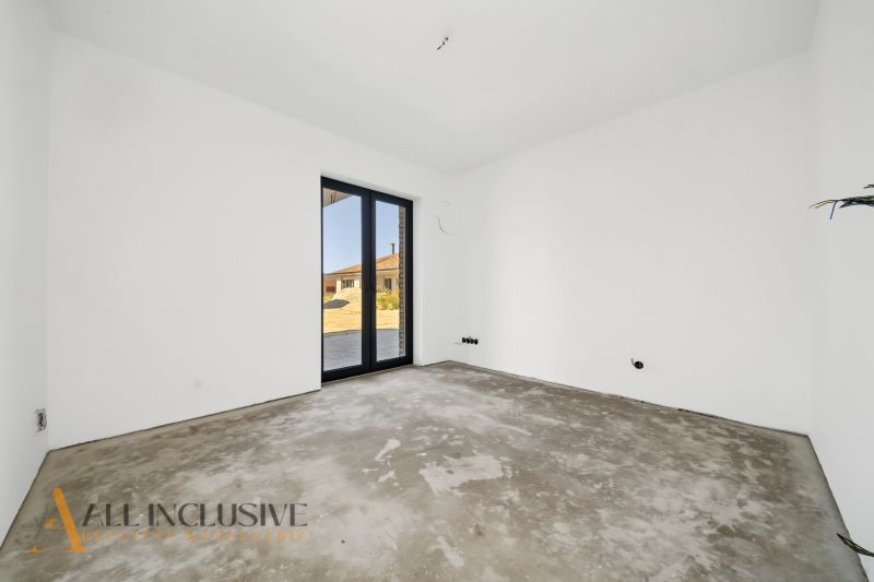 A room with white walls and a large window in a family house.