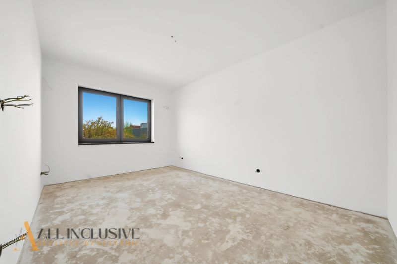 A room in a family house with a concrete floor and a large window.