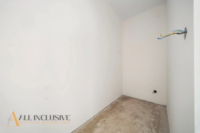 Empty room with white walls and a raw floor in a family house.