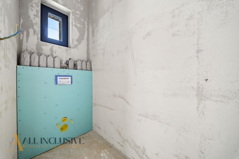 Unplastered bathroom with preparation for toilet installation in a family house.