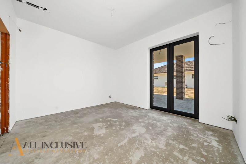 The interior of a family house with a concrete floor and large windows to the terrace.