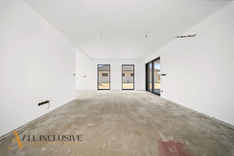 A spacious room in a family house with a concrete floor and large windows.