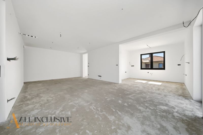 A spacious room in a family house with a concrete floor and a large window.