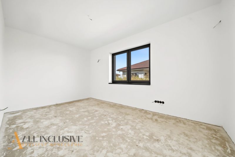 An unfurnished room with white walls and a large window in a family house.