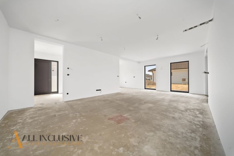 Interior of a family house with a concrete floor and large windows.