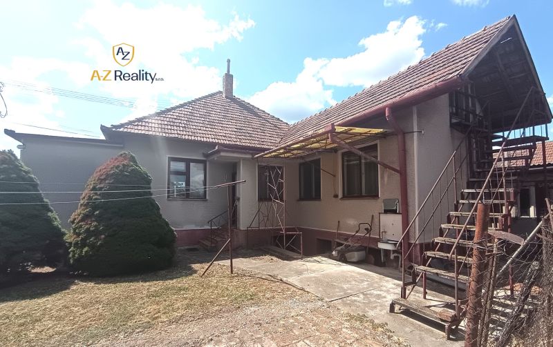 A family house in Bánov with a metal staircase and a fenced garden.