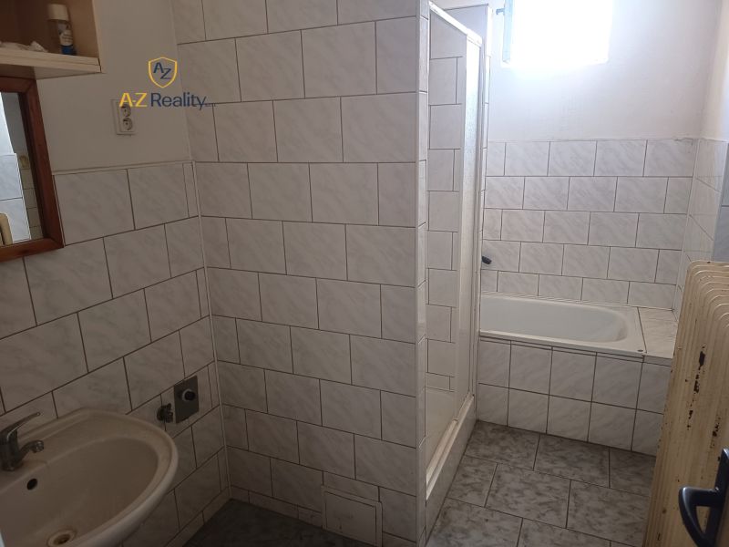 A bathroom with a bathtub, shower, and sink tiled in a family house.