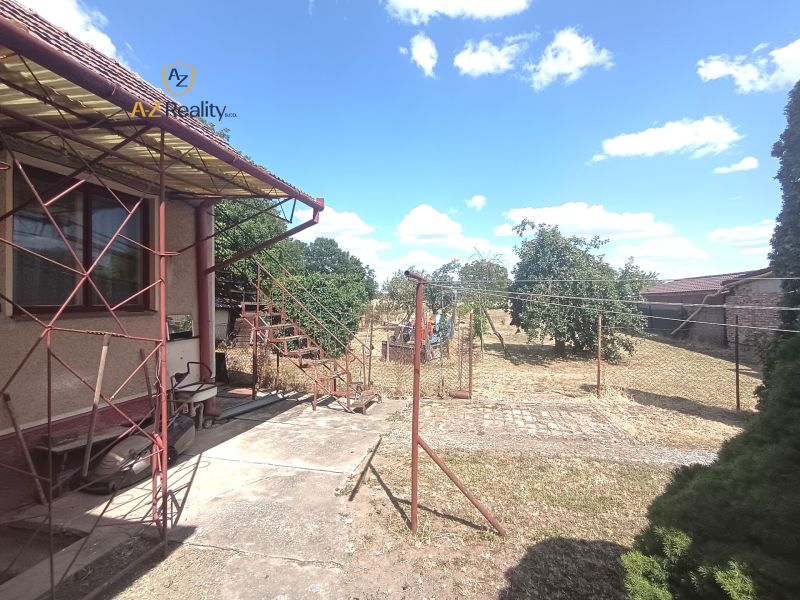 A family house in Bánov with an external staircase and a yard with fruit trees.
