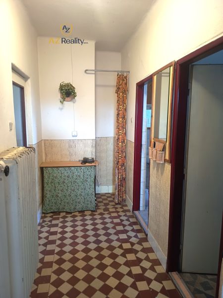 A hallway with retro tiles, a small table, and a curtain in a family house.