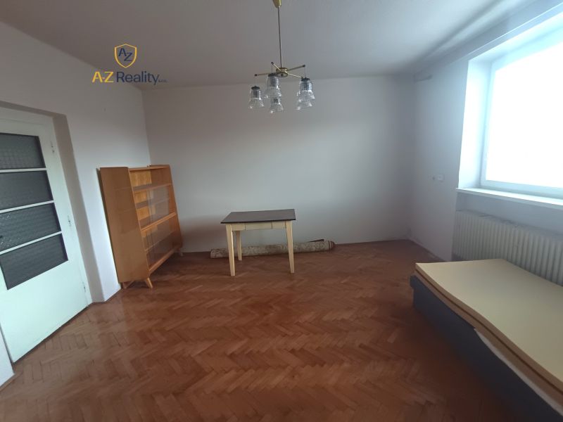 A bright room with a wooden decor floor, a table, and a dresser in a family house.