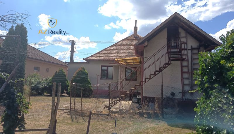A family house in Bánov with an external staircase, a sloped roof, and a garden.