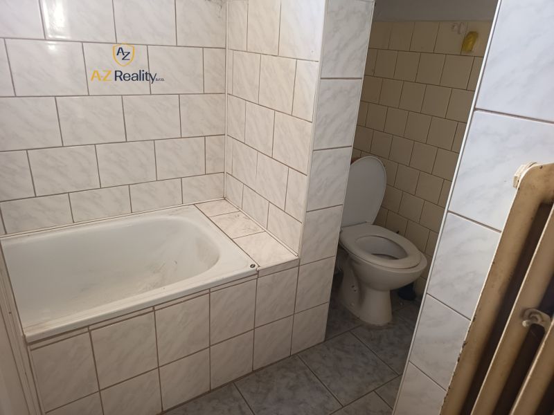 Bathroom in a family house with a bathtub and toilet tiled with light tiles.