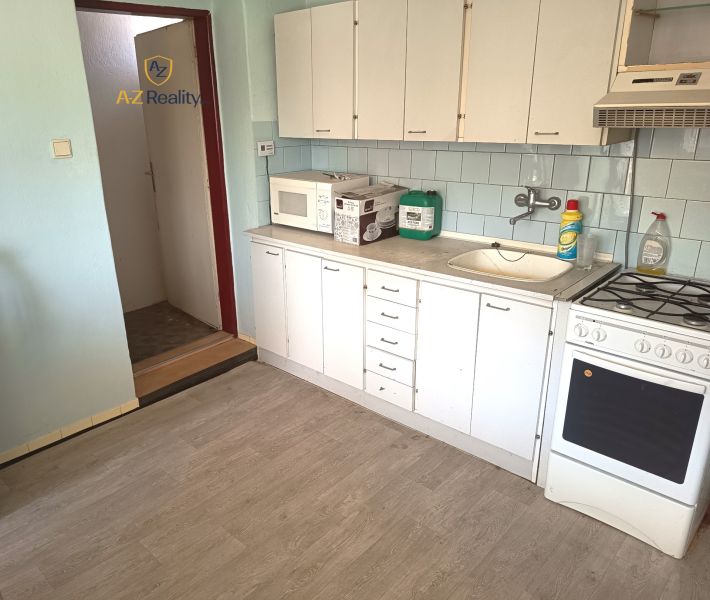 A kitchen with white cabinets, a microwave, and a wooden decor floor in a family house.