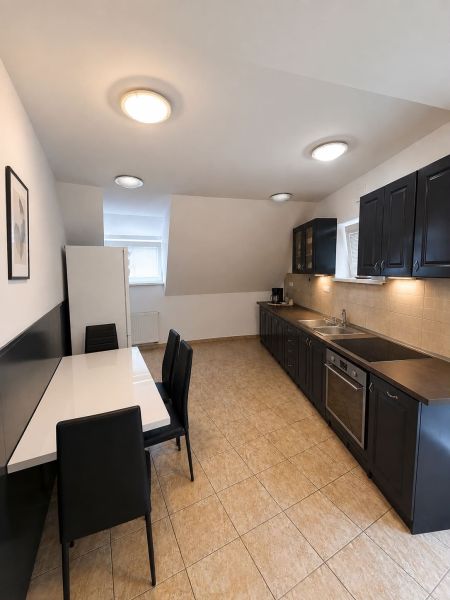 A kitchen in a 2-room apartment with black furniture and light ceramic flooring.
