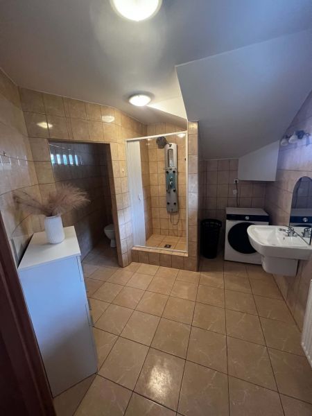 A bathroom in a 2-room apartment with a bathtub, sink, and washing machine, tiled with light tiles.